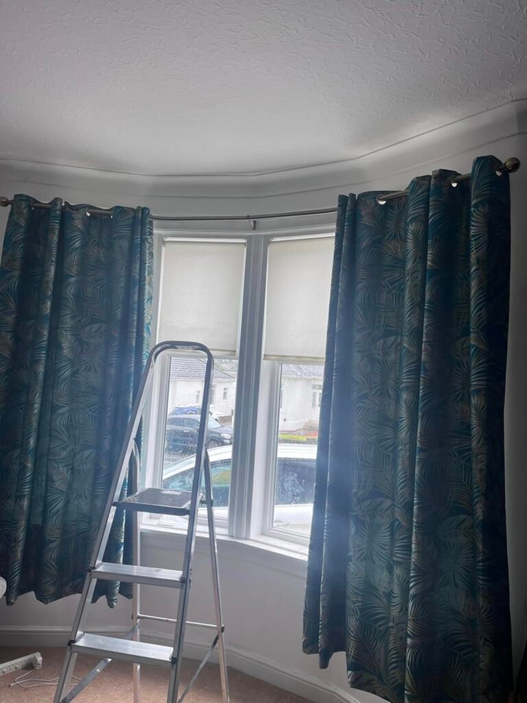 Angled bay window curtain pole with elbow connectors installed in living room
