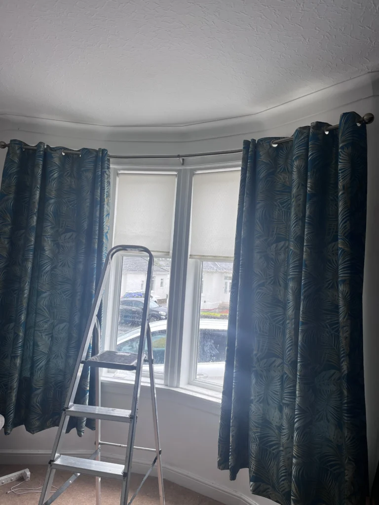 Chrome bay curtain pole fitted around curved bay window.