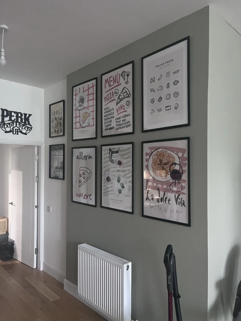 Gallery wall of assorted artwork arranged in a grid pattern in a hallway